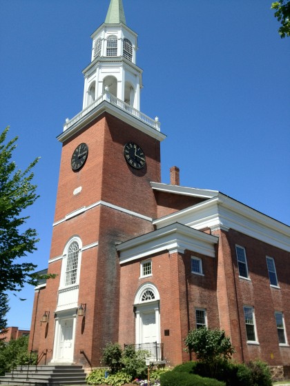 A brick church with a tall white steeple.